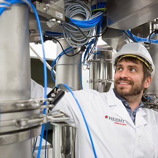 Mann in Schutzkleidung steht unter einer Maschine