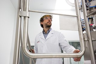 Man with protective clothing on stairs in front of technical equipment