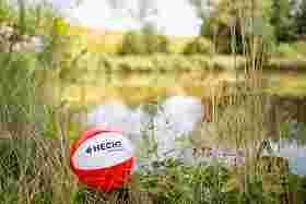 Red and white ball with company logo lying on the shore of a lake