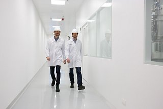 Deux hommes en tenue de protection marchent le long d'un couloir en souriant