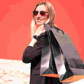 Frau mit Sonnenbrille und Einkauftüten über der Schulter