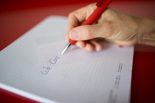 Person holds pen in hand and writes on a pad