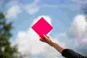 Eine Hand hält eine rote Raute in den Himmel